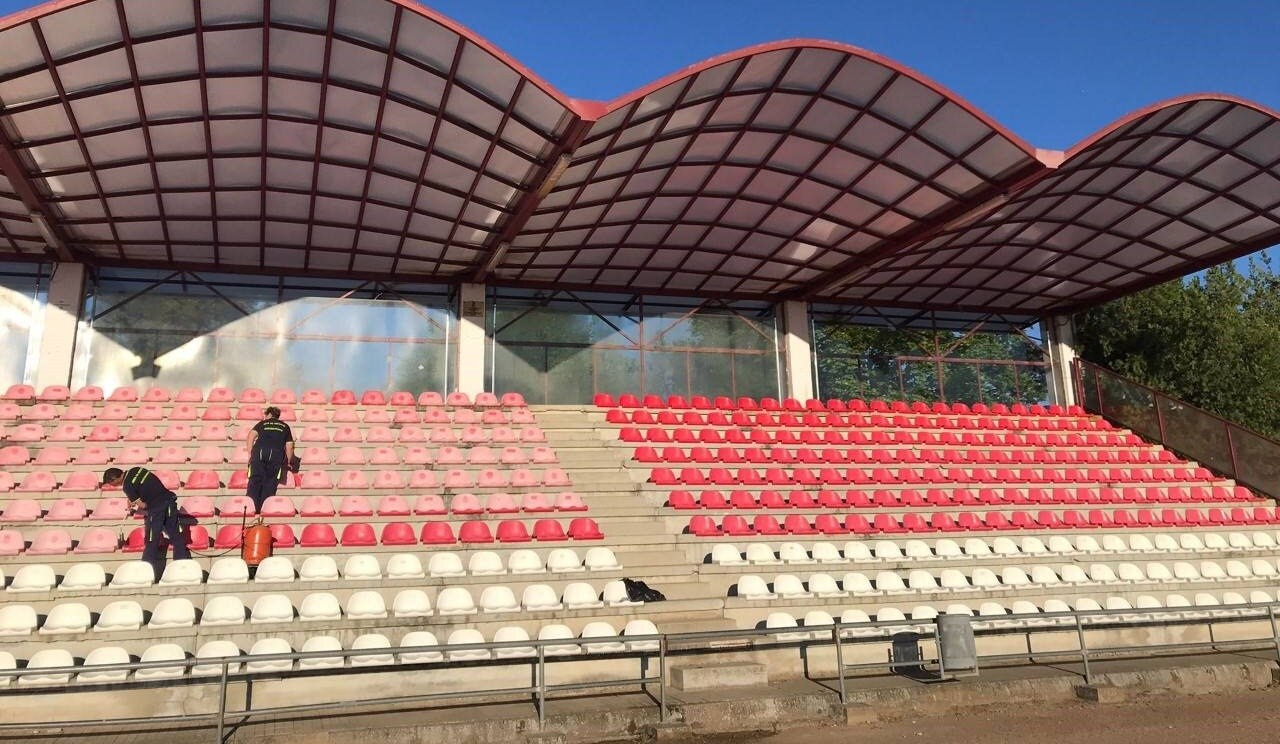 Los operarios municipales pintan las gradas techadas del estadio municipal de fútbol 
