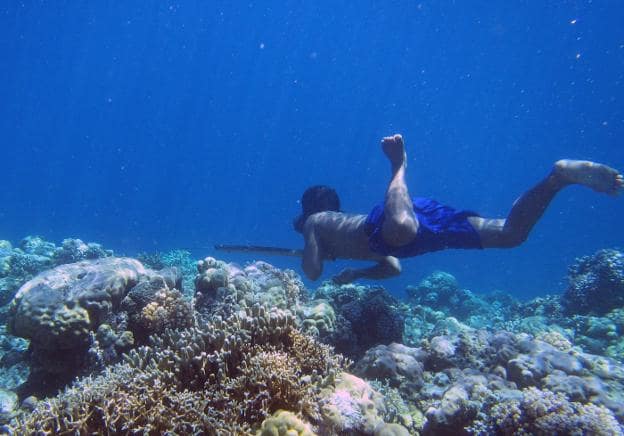 Un pescador bajau acecha a los peces en apnea entre los arrecifes de coral. Arriba, un poblado de palafitos en Malasia. :: afp/