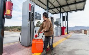 Un operario llena una garrafa de combustible en una cooperativa en el valle del Jerte. :: A. Solé/