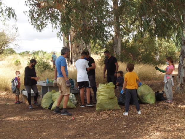 Algunos de los voluntarios, junto a la basura que recogieron a orillas del Guadiana. / HOY