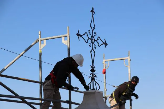 Operarios instalan la cruz de hierro rehabilitada. / AV