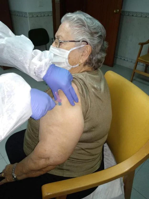 Bomberos del CPEI desinfectan la Formacionistas. A la derecha, una mujer de 'La Coronada' se vacuna. / CEDIDAS