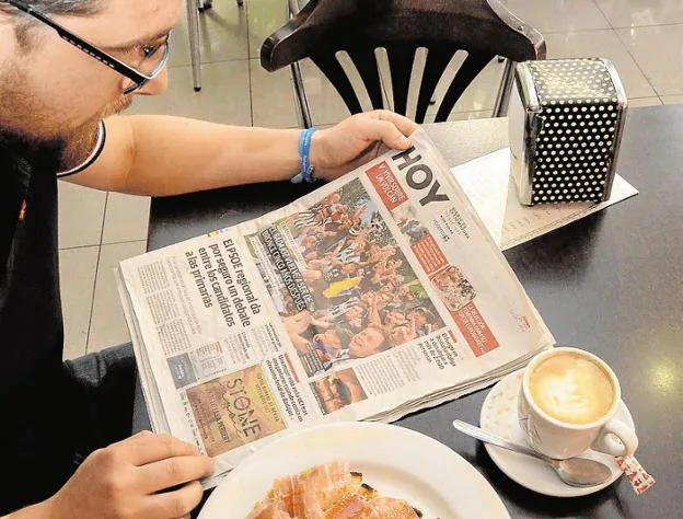 Un pacense leyendo el periódico en un bar de Badajoz. / HOY