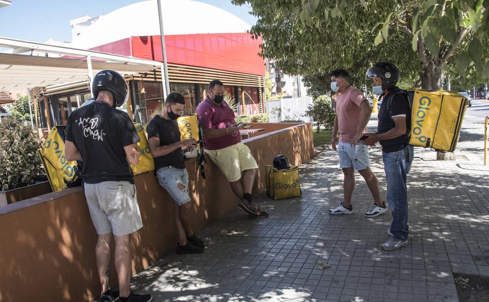 'Riders' de Glovo esperan en María Auxiliadora (Badajoz) a que les lleguen pedidos a través de su aplicación. /Pakopí