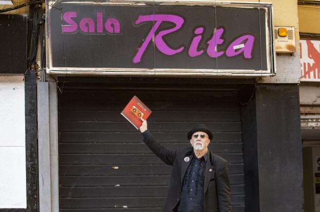 Paco Lobo con el libro ante la Sala Rita de la Madrila, un icono de la movida cacereña de los ochenta. / JORGE REY