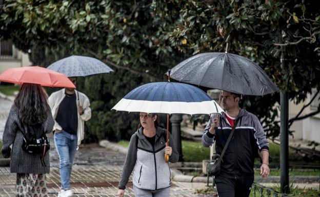Imagen de archivo de personas paseando por Badajoz con paraguas./HOY