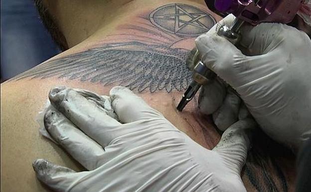 Un tatuador realiza un tatuaje. 