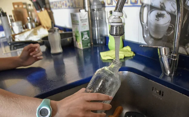 Una persona llena una botella de agua en un grifo. 